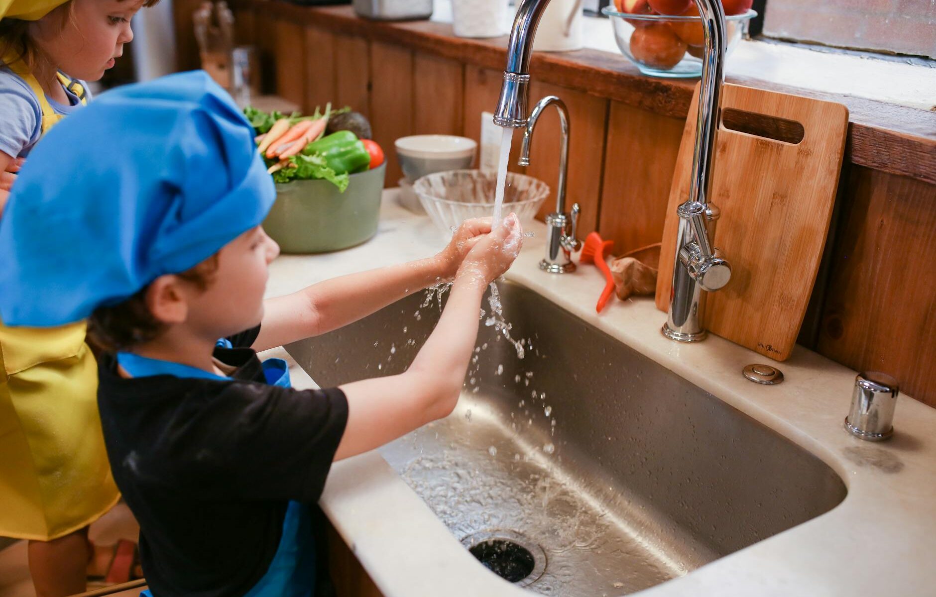 boy in blue shirt and blue cap in bathtub